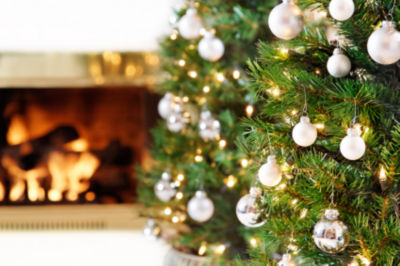 Glittering silver and white Christmas tree decorations by a warm fire