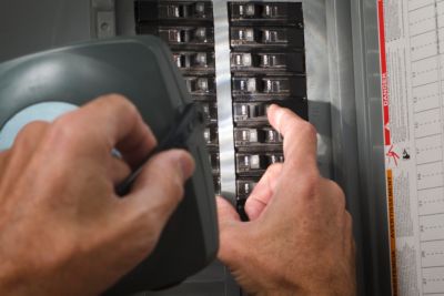 man checking circuit breaker at residential service panel