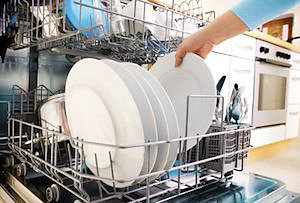 Hand grabbing clean plates out of dishwasher