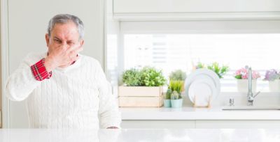 Man holding nose due to fishy odor from garbage disposal