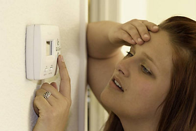 Distressed woman adjusting thermostat