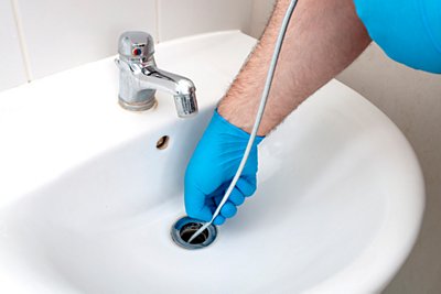 Drain snake being use to clean bathroom sink drain