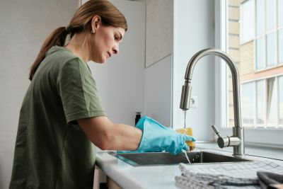 woman cleaning her kitchen drain at home