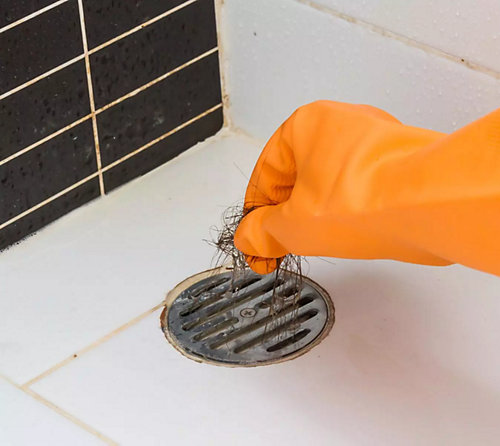Shower drain being cleaned by hand - Mr. Plumber by Metzler & Hallam