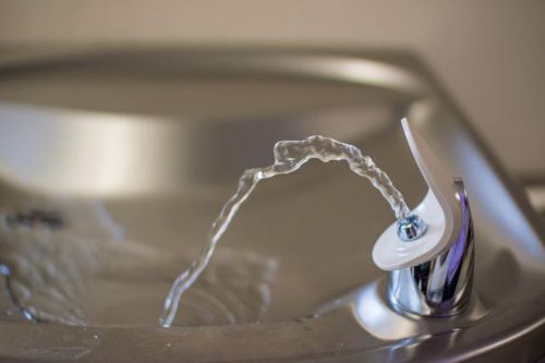 Closeup of a drinking fountain spout with water coming out of it