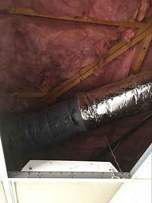 Looking up at attic ceiling with air duct beneath insulation