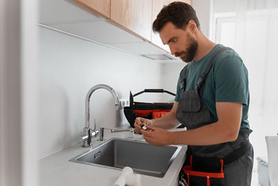 Dallas plumber installing eco-friendly water-saving faucet in modern kitchen.