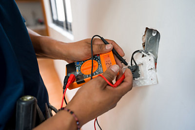 Close-up on an electrician fixing an electrical outlet and measuring the voltage at a house – home improvement concepts 
