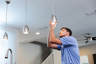 Electrician inspecting light in customer's home