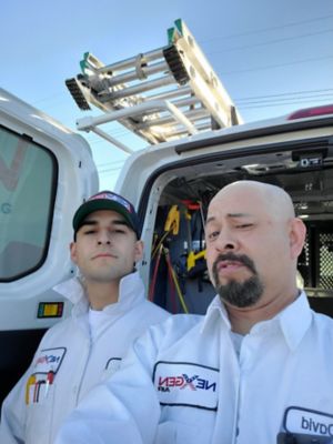 Two NexGen employees taking a selfie behind a service van