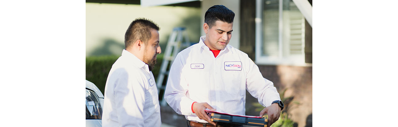 NexGen technicians standing outside a house looking at a clipboard