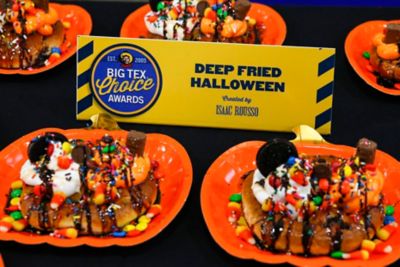 A deep fried halloween dessert with halloween candy on top of a soft pretzel