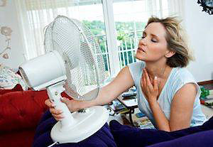 Woman with fan on face blowing hair
