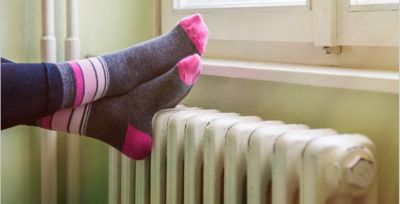 Feet with socks crossed on old furnace