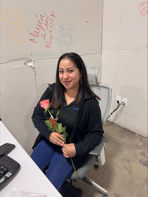 A female employee sitting at a desk holding a rose