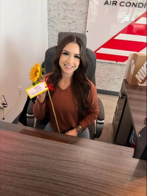 A female employee sitting at a desk holding a sunflower