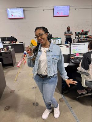 A female employee standing holding a sunflower next to her face