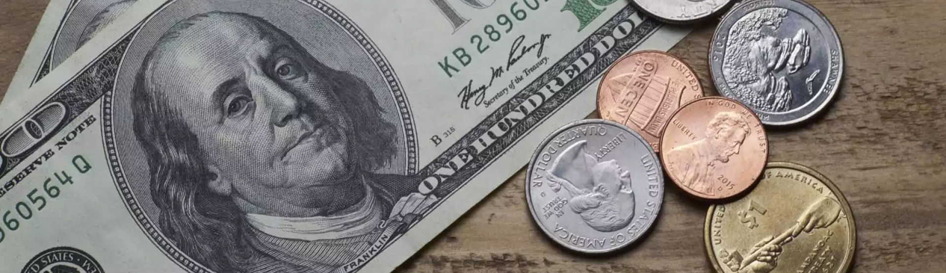 A stack of dollar bills and coins on a table.