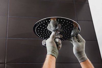 The worker's hands install the head of the built-in shower faucet.
