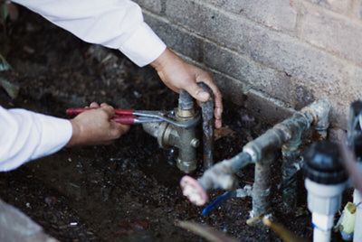 plumber repairing pipe leak behind house in Anaheim