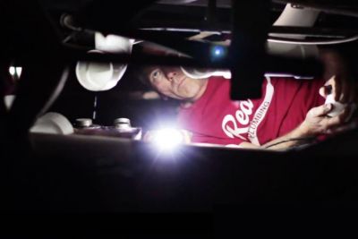 Red Cap tech lying in a small space to access a plumbing pipe