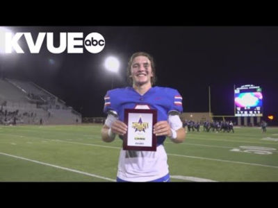 Football player Logan Mitchell holding the Athlete of the Week award on the field.