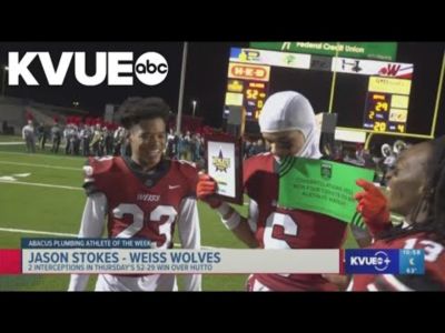 Football player Jason Stokes holding the Athlete of the Week award on a football field.