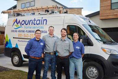 Four techs standing outside in front of a work van