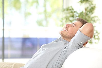 A man relaxing in a comfy chair on a screened in porch