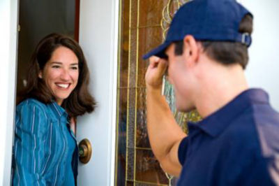 Woman opening door and smiling at technician