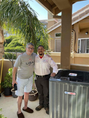 Two men standing side by side next to an AC unit.