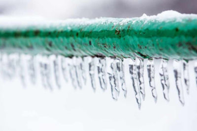 green frozen pipe with icicles hanging