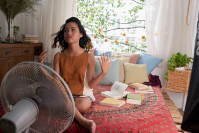 College aged girl in her room with fan