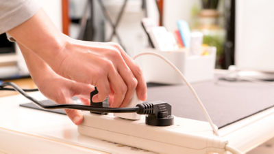 Hands adjusting multiple plugs in surge protector