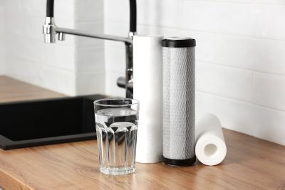 Various types of water filters sitting on a counter next to a glass of water