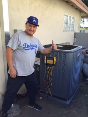 Man in Dodgers shirt giving thumbs up in front of AC unit