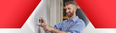 Technician setting thermostat to ideal, cost-saving indoor temp
