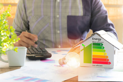 Men who are calculating cost savings from energy. Hand holding a pen. Detail of house efficiency rating on digital tablet screen. Concept of ecological and bio energetic house. Energy class.