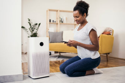 African American woman adjusting air purifier at her house