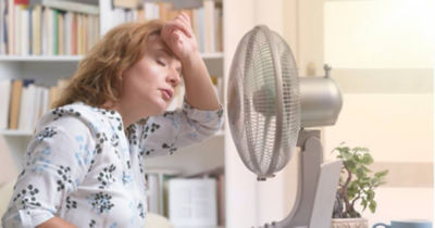 Overheating woman cooling down with fan