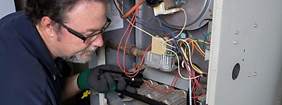 HVAC technician inspecting the inside of a furnace