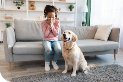 Girl indoors with dog blowing her nose with a tissue.