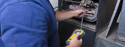 9. HVAC repair technician testing indoor furnace - Thomas & Galbraith Heating, Cooling, & Plumbing