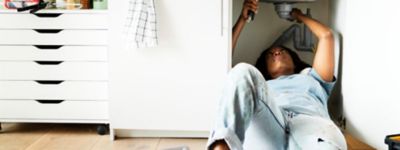 A person lying on the floor under a sink