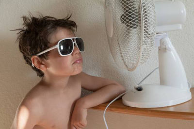 Kid with sunglasses on in front of fan to cool down
