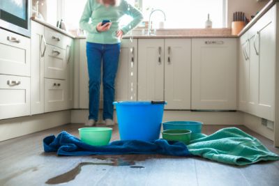 women standing in the kitchen looking at buckets that are catching the water from her leak