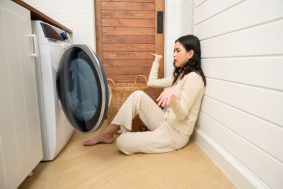 Exhausted  Asian young woman with dirty clothes , doing laundry in home