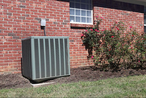 A heat pump outside of a brick building