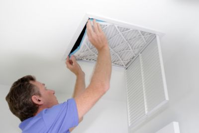 Man changing an air filter in ceiling vent