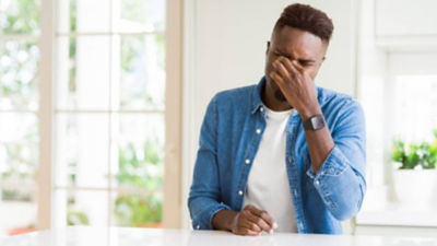 Man grimacing while holding nose inside home